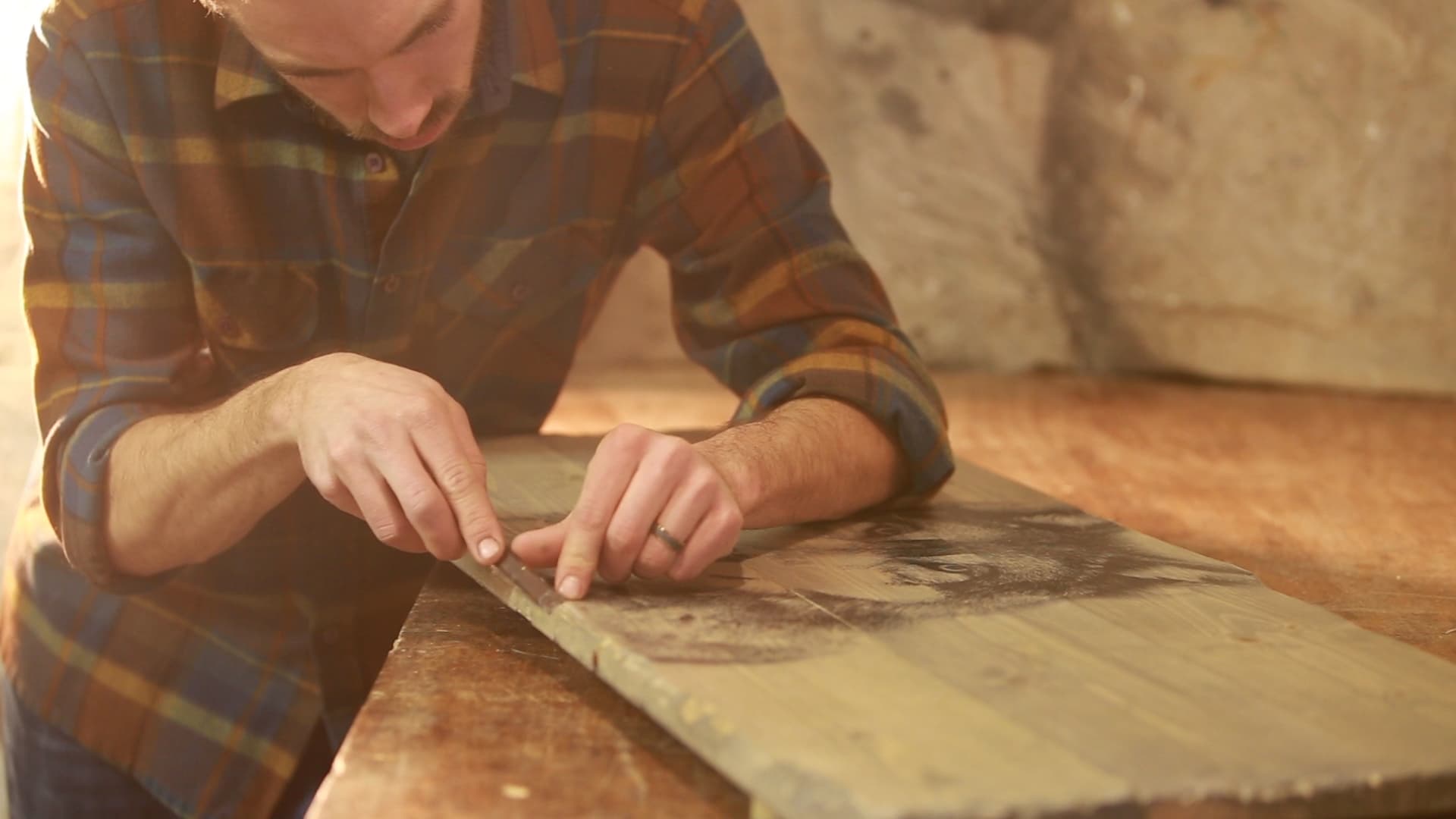 Ross hand-finishing a portrait printed on a wooden board at the Unrefined Art workshop